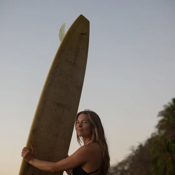 Charlotte holding a longboard at sunset